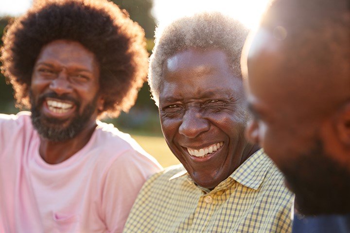 Three African American men sitting together and laughing.