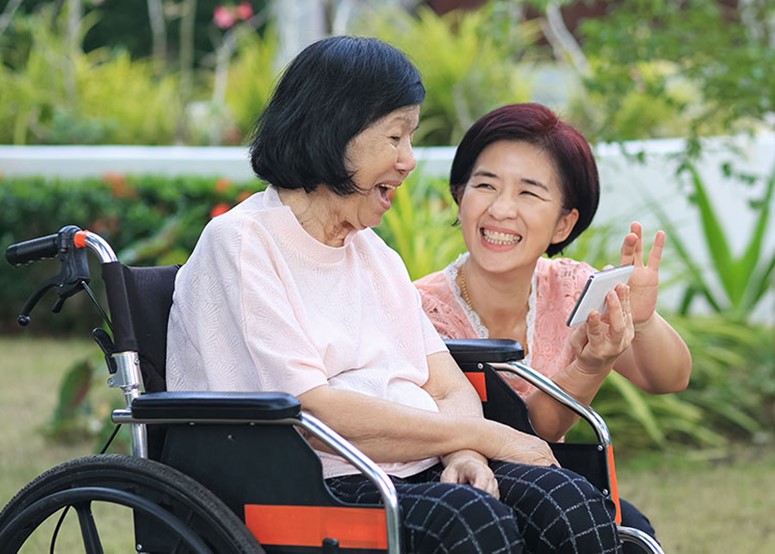 An older person in a wheelchair with her care partner