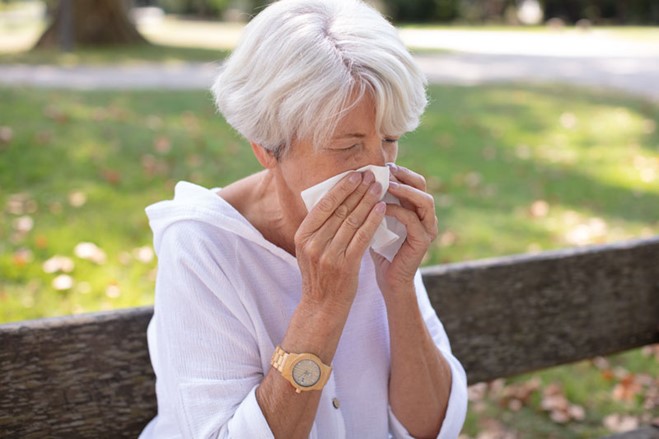 woman sneezing into a tissue
