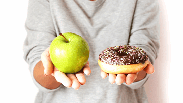 A woman holding an apple in one hand and a donut in the other