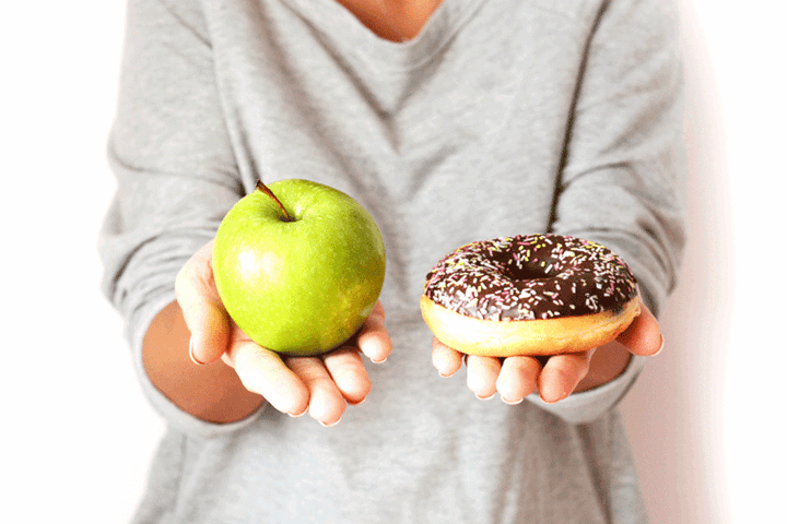 Image of woman holding an apple and a donut