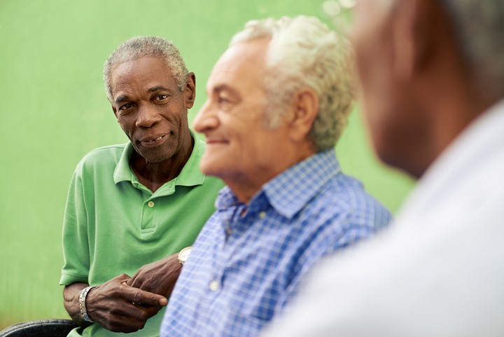 Older adult men smiling at each other.