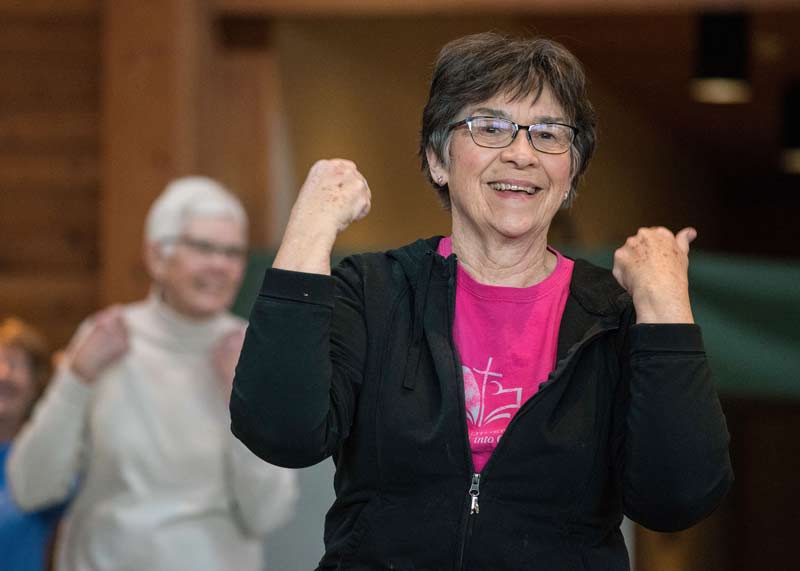 Woman smiling and raising her arms in a get fit class
